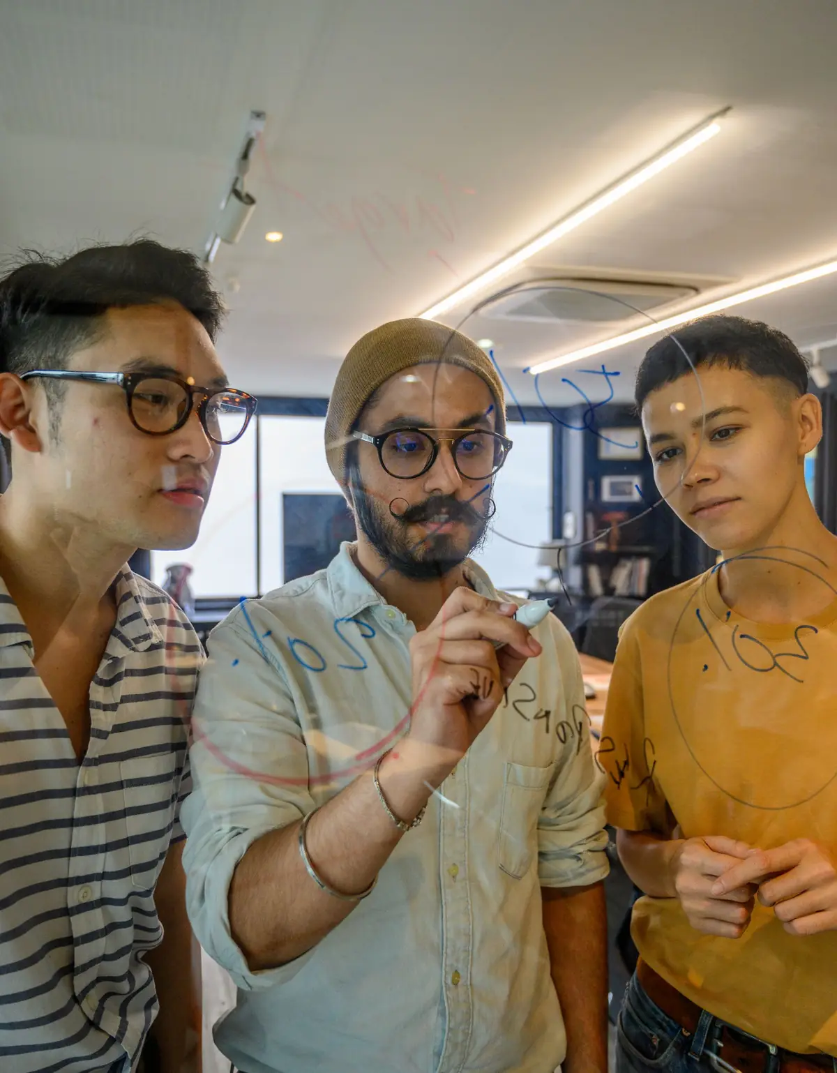 Trois collègues qui annotent un tableau en verre